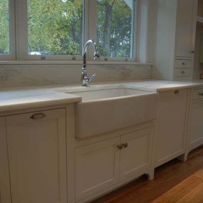 Modern kitchen featuring a white farmhouse sink and marble countertops.