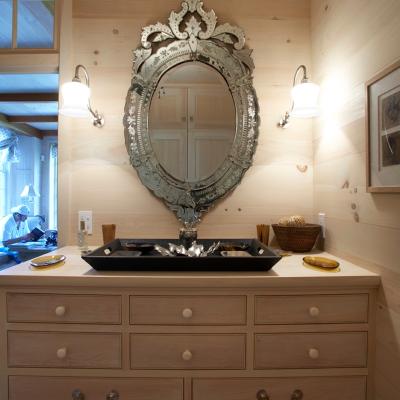 Interior bathroom featuring a decorative mirror above a wooden vanity with a black sink.