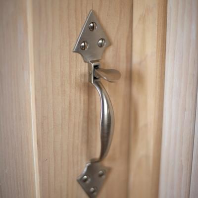 Close-up of a metallic door handle on a light wooden door.