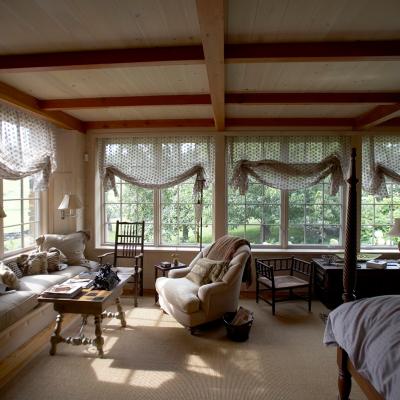 Cozy sunlit room with windows, soft furnishings, and a wooden table.
