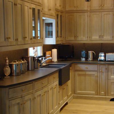 Modern kitchen with wood cabinetry, black countertop, and stainless steel appliances.