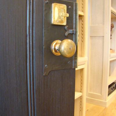 Close-up of an ornate door handle and lock on a wooden door.