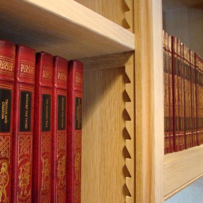 Rows of red-bound books with gold lettering on a wooden shelf.