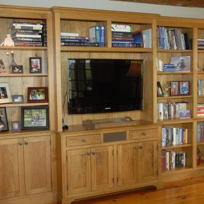 Wooden shelves with books, photos, and a TV unit in a cozy living room.