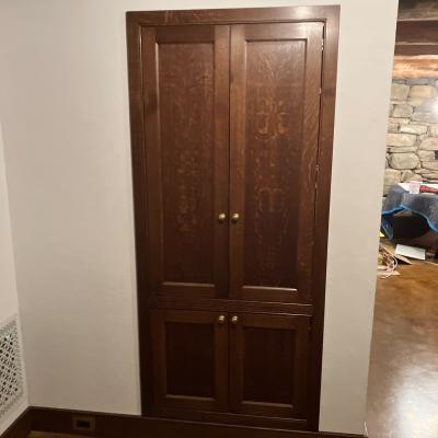 Wooden cabinet with two doors, set against a white wall in a rustic interior.