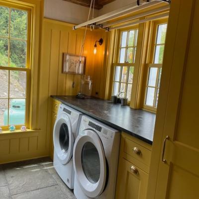 Bright laundry room with yellow walls, washer and dryer, and large windows.