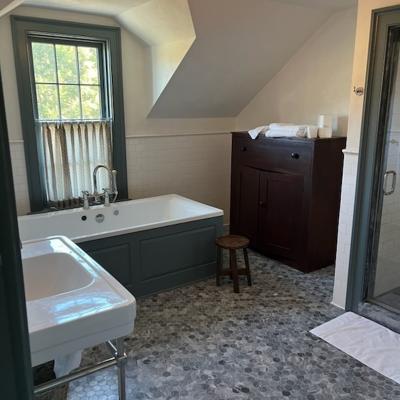 Bright bathroom featuring a tub, sink, wooden cabinet, and hexagonal tile floor.
