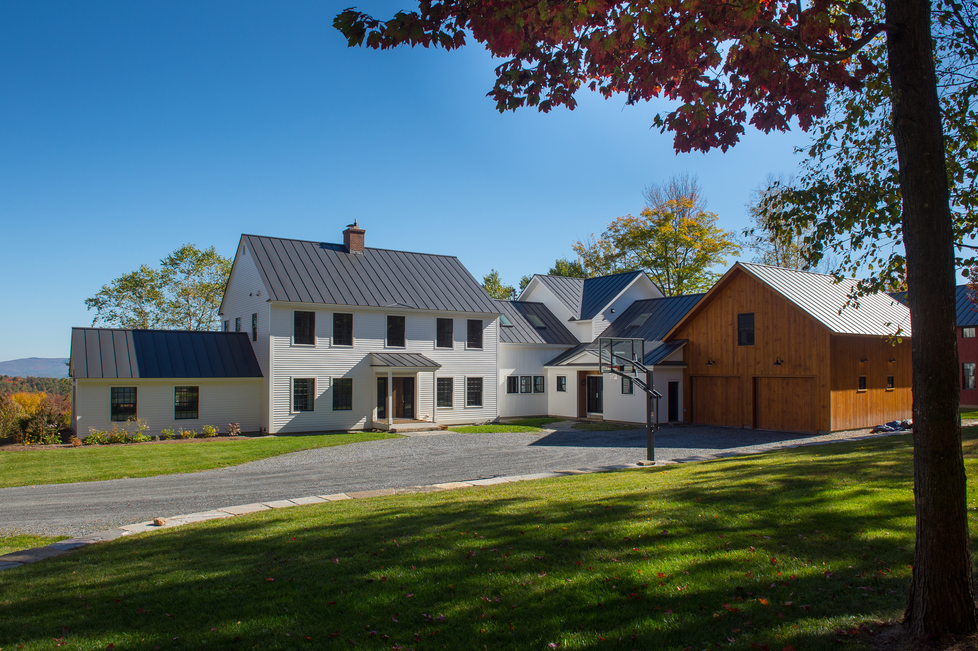 white and wooden buildings on green lawn with large driveway